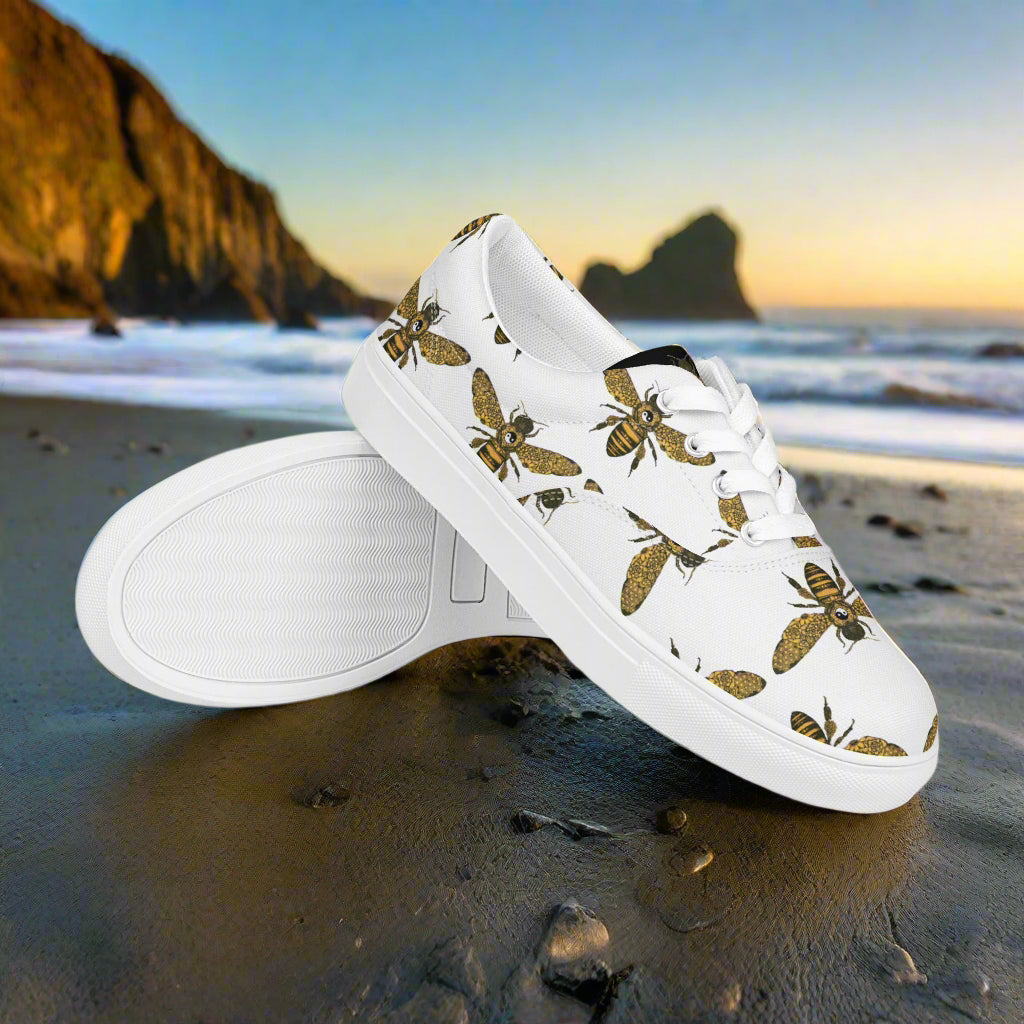 WildSage Market lace-up canvas shoes with bee print on white background at the beach