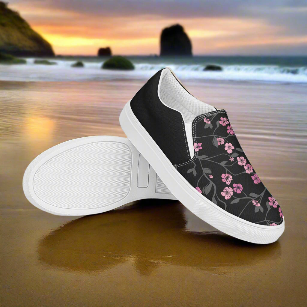 Black Cherry Halftone Slip-on Canvas Shoes with floral design on a beach backdrop