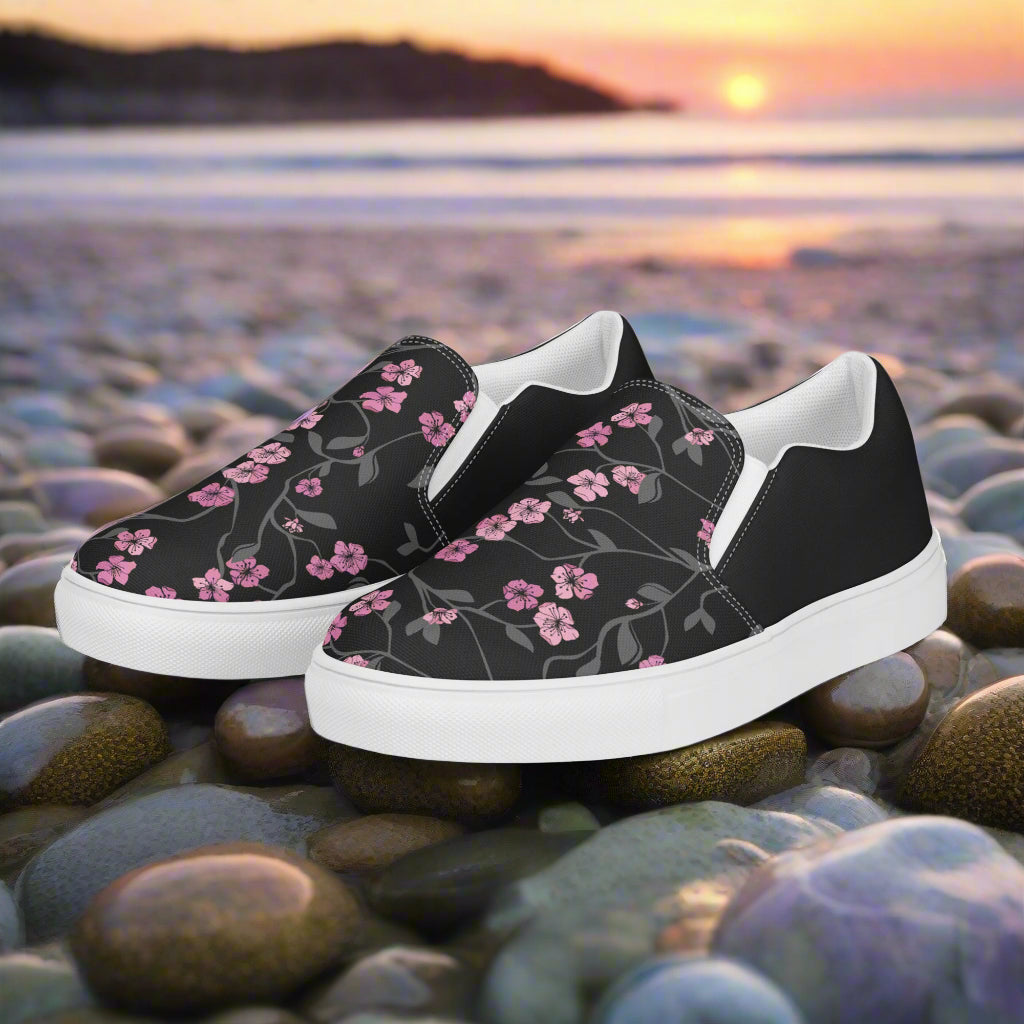 Black Cherry Halftone Slip-on Canvas Shoes with Floral Design on a Beach Pebble Background
