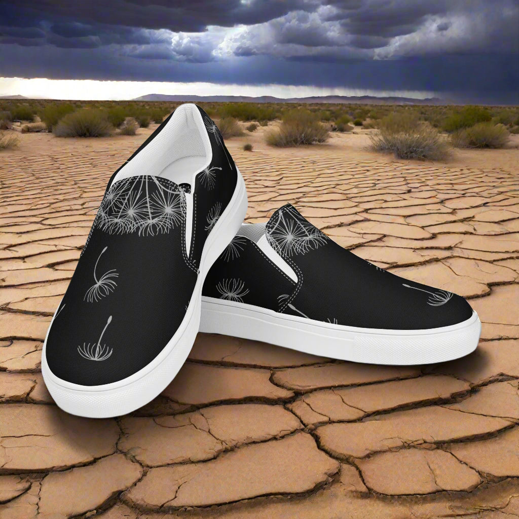 Black Dandelion Floral Print Slip-on Canvas Shoes on a dry landscape, stylish and comfortable for everyday wear