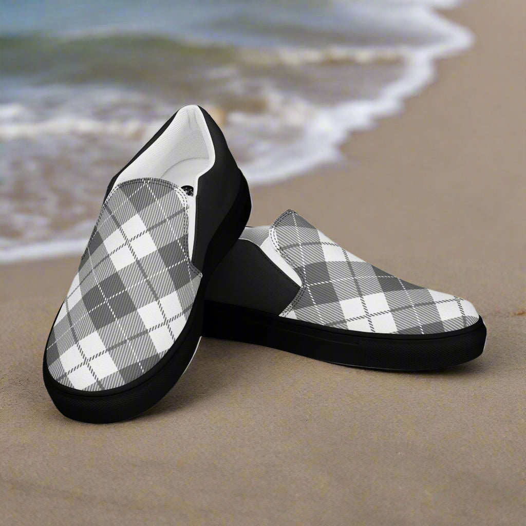 WildSage Market Black Plaid Halftone Slip-On Canvas Shoes on beach sand with ocean waves background