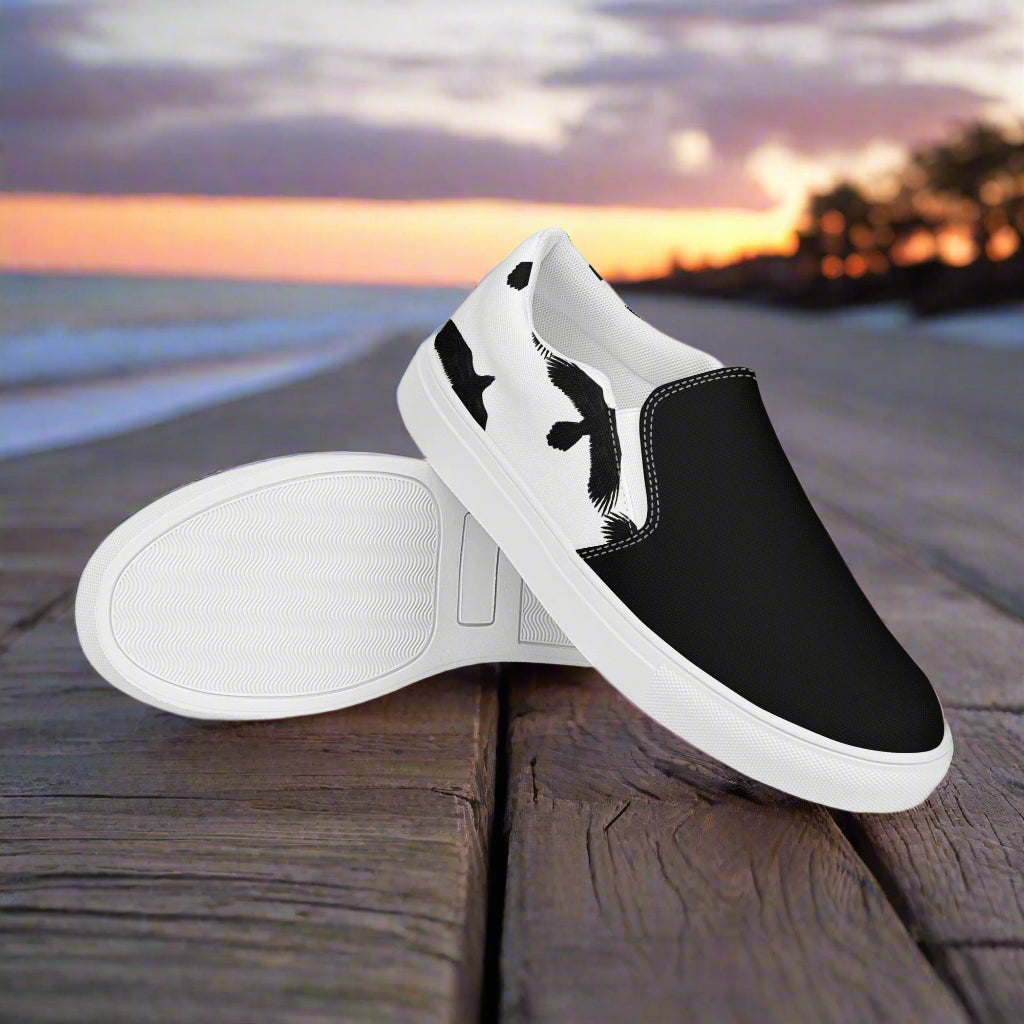 Black Ravens White Two Tone Slip-on Canvas Shoes on a wooden beach deck at sunset