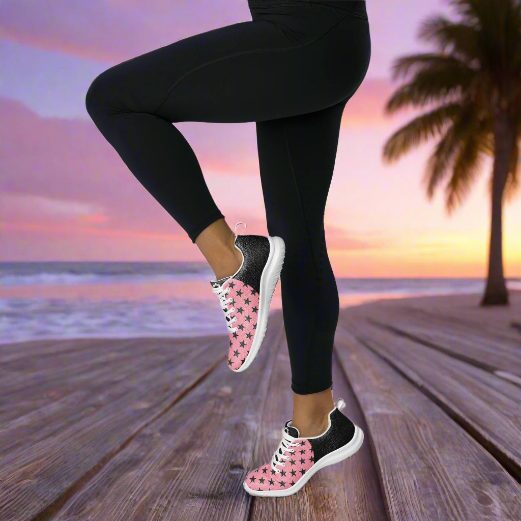 Black Stars Pink Halftone Womens Athletic Shoes worn by person standing on wooden boardwalk at sunset
