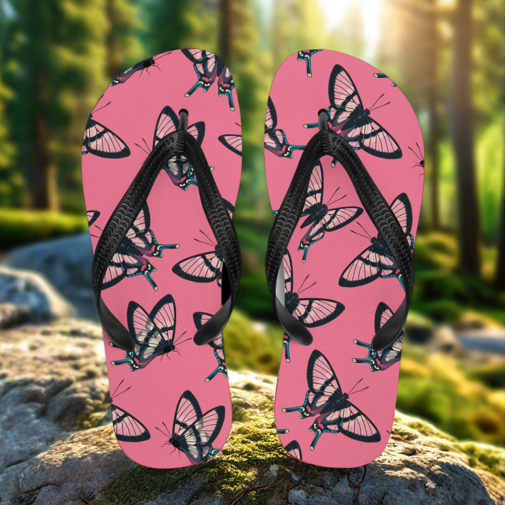 WildSage Market butterfly print flip-flops with black straps and vibrant pink background