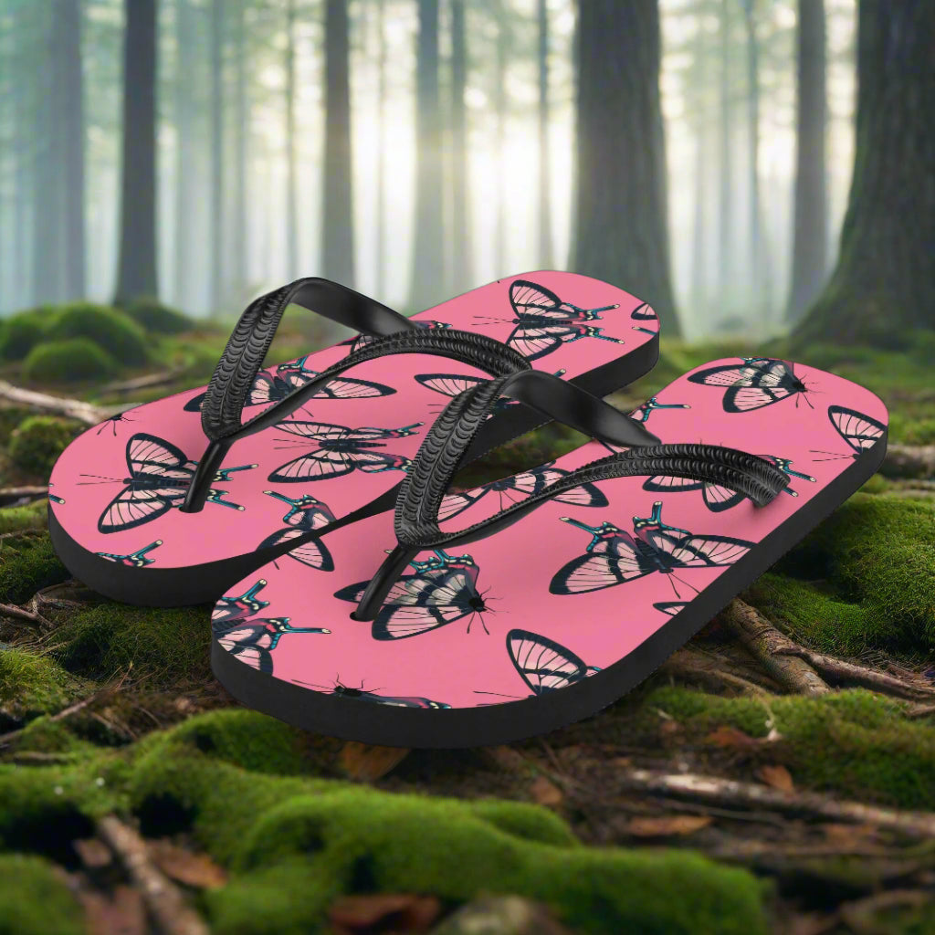 WildSage Market butterfly print flip-flops on a forest floor with vibrant pink design and black straps