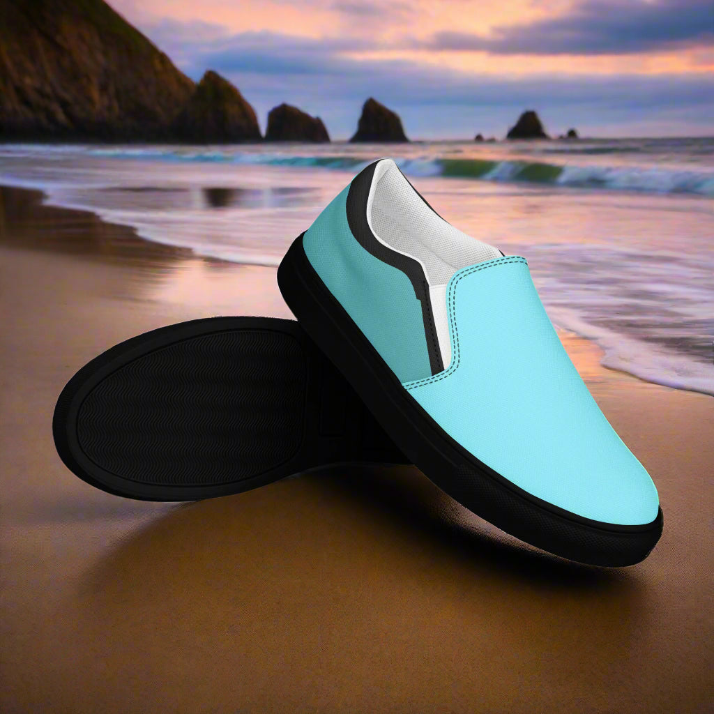 WildSage Market teal slip on canvas shoes with black soles displayed on a beach at sunset