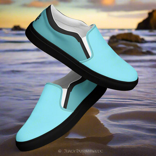 WildSage Market teal slip on canvas shoes with black soles resting on a beach shore background