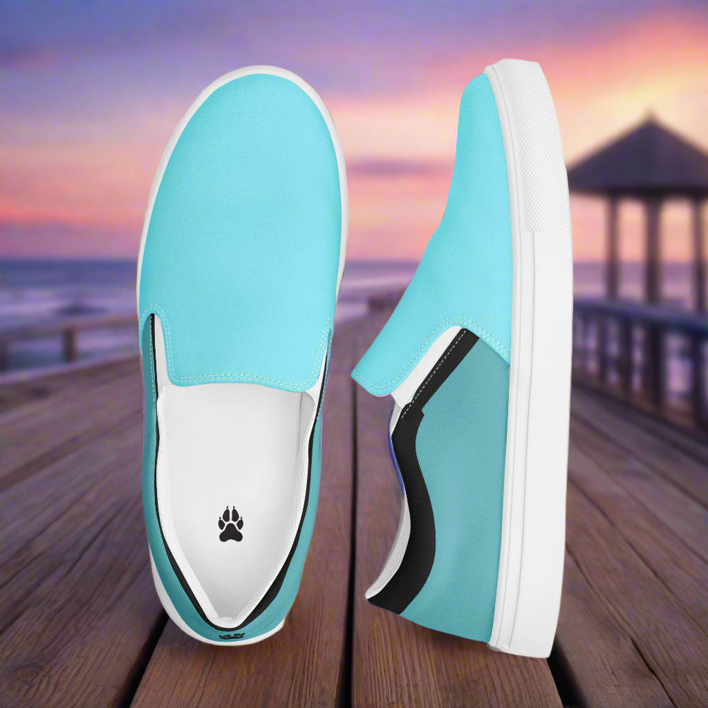 WildSage Market teal slip on canvas shoes with white soles displayed on wooden dock at sunset
