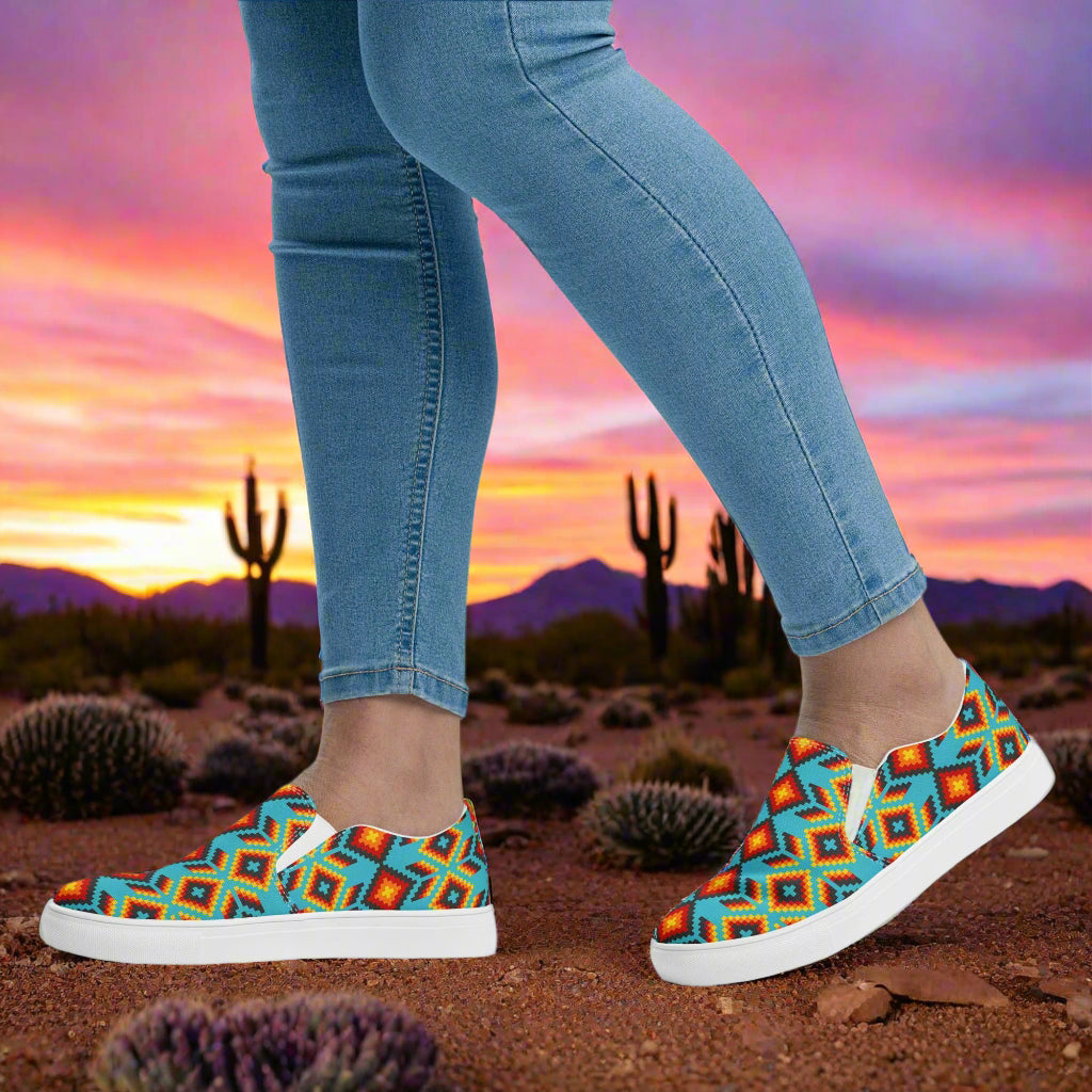 Huichol Southwest Print Slip-on Canvas Shoes worn with denim jeans against a vibrant sunset backdrop