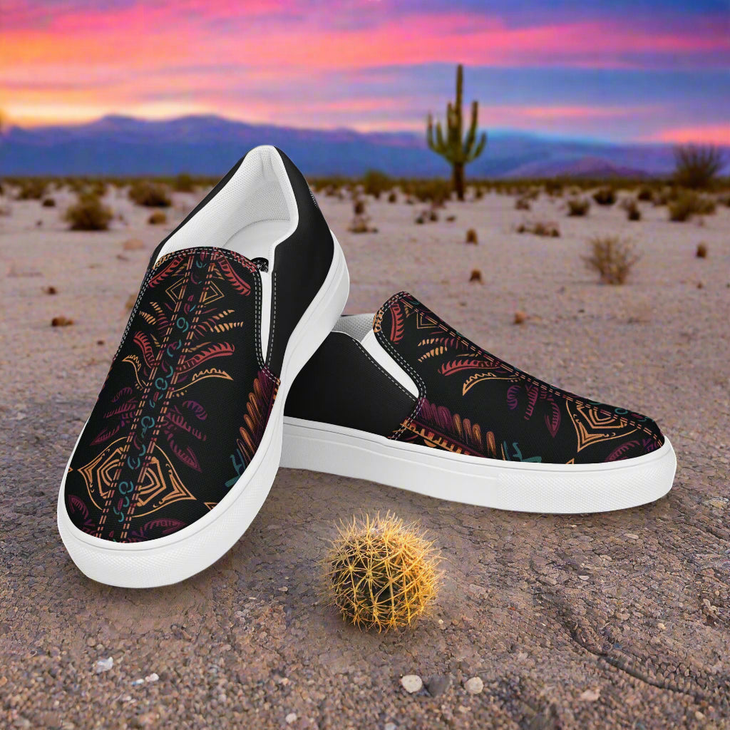 Iktomi Halftone Slip-on Canvas Shoes with colorful tribal pattern against desert backdrop