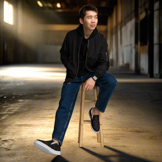 Mens Crimson Diamond Slip on Canvas Shoes worn by a young man seated on a stool in an industrial setting