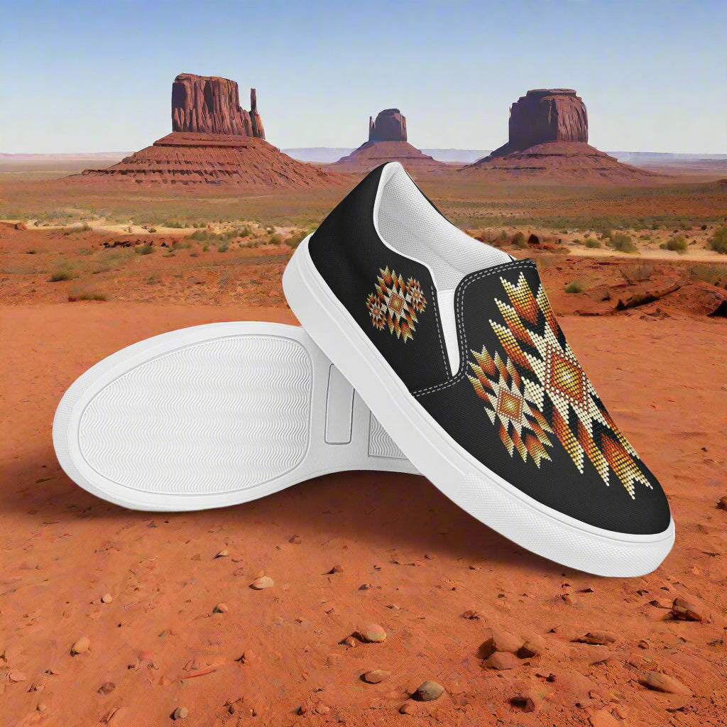Mens Southwest pattern slip-on canvas shoes featuring vibrant tribal designs against a desert backdrop