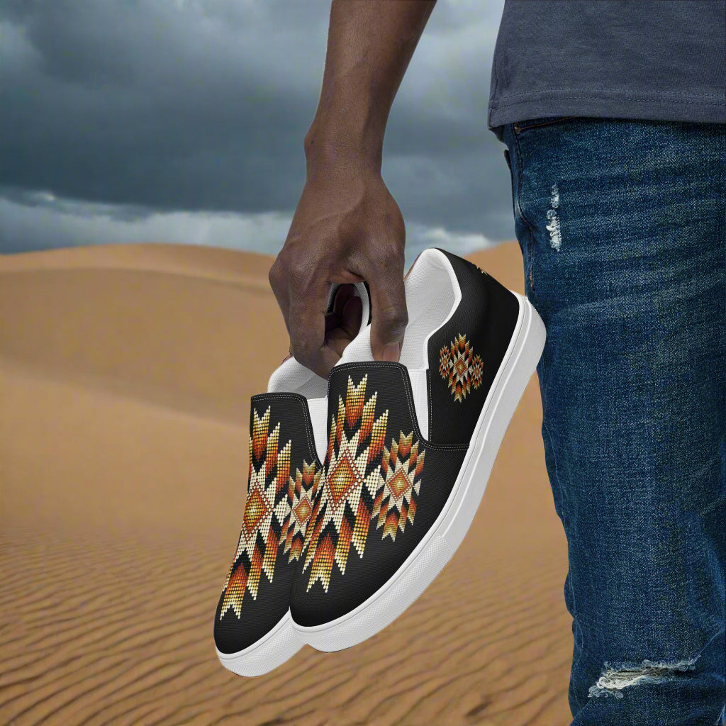 Mens Southwest pattern slip-on canvas shoes featuring vibrant tribal designs on a sandy background
