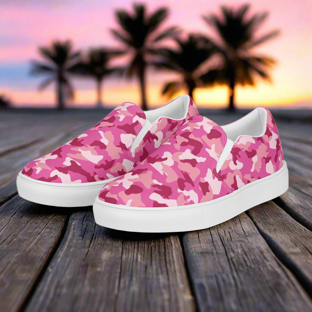 WildSage Market pink camo slip on shoes with white soles on wooden deck at sunset