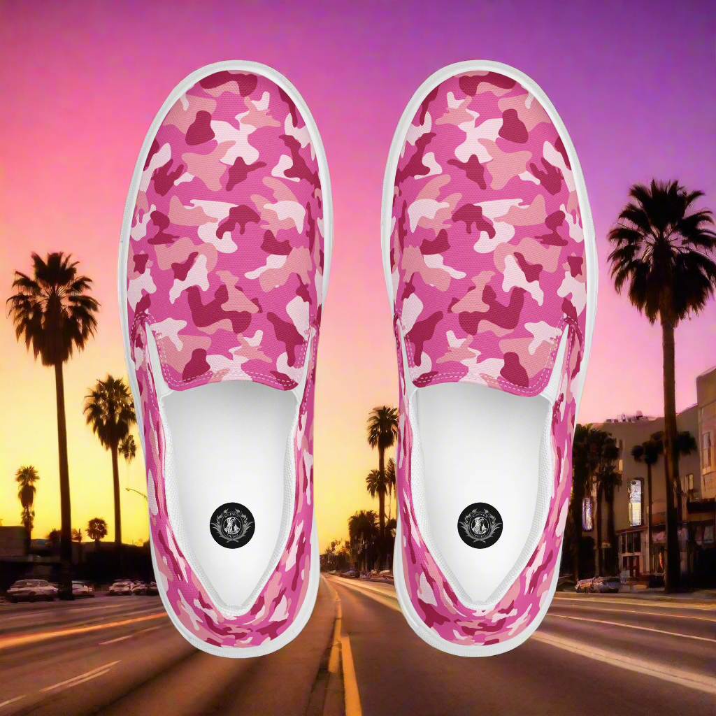WildSage Market pink camo slip on shoes with white soles displayed over a sunset city street background