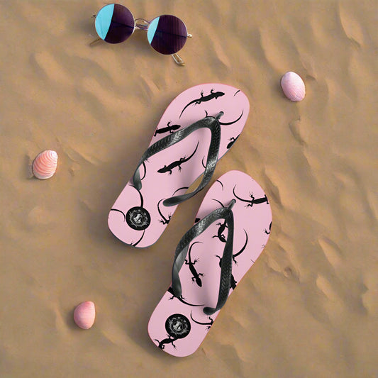 Pink lizard flip-flops by WildSage Market with black lizard print on a sandy beach