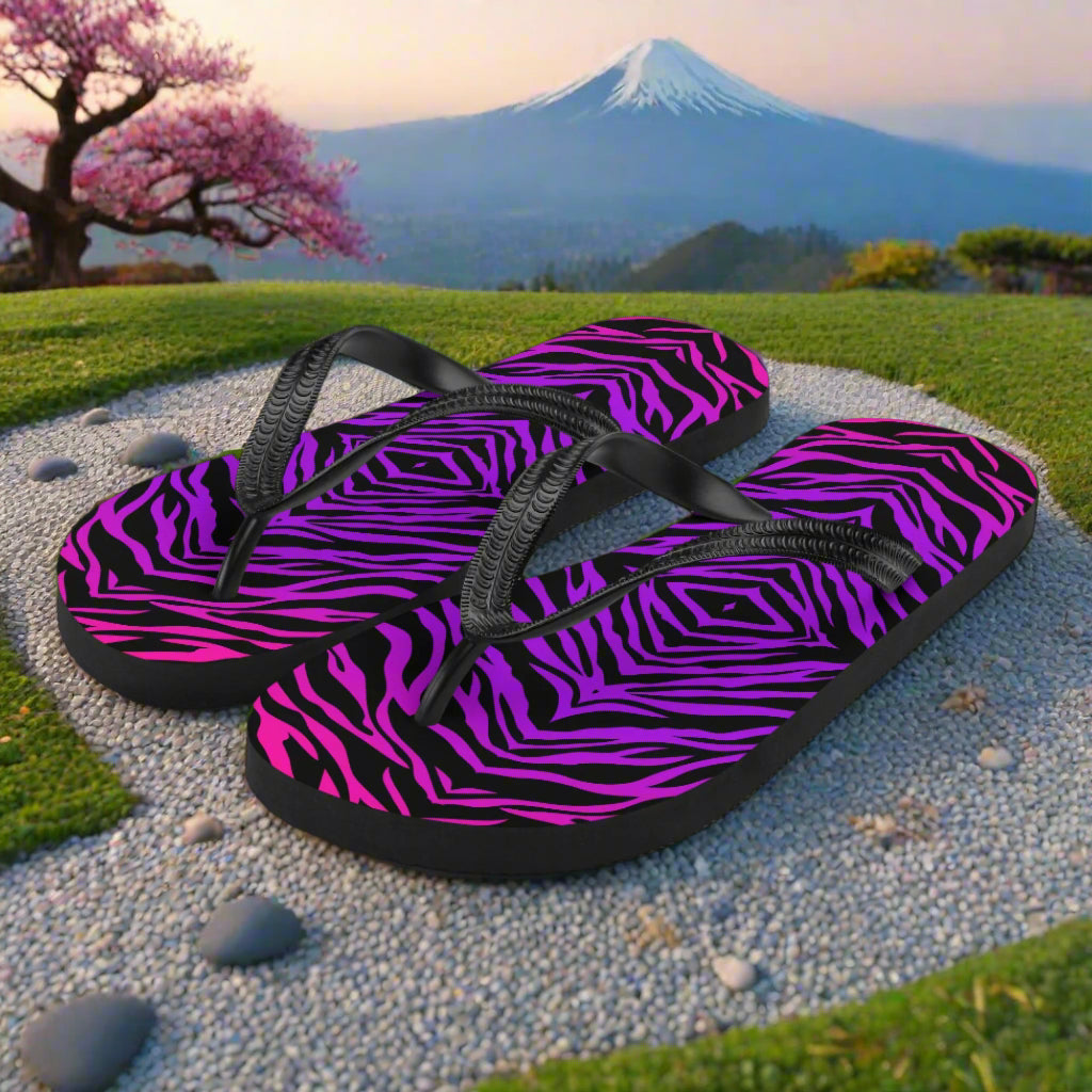 WildSage Market purple zebra print flip-flops with black straps on a scenic outdoor background