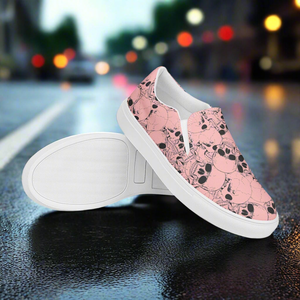 WildSage Market slip on shoes featuring a pink skull pattern with white soles on a street background