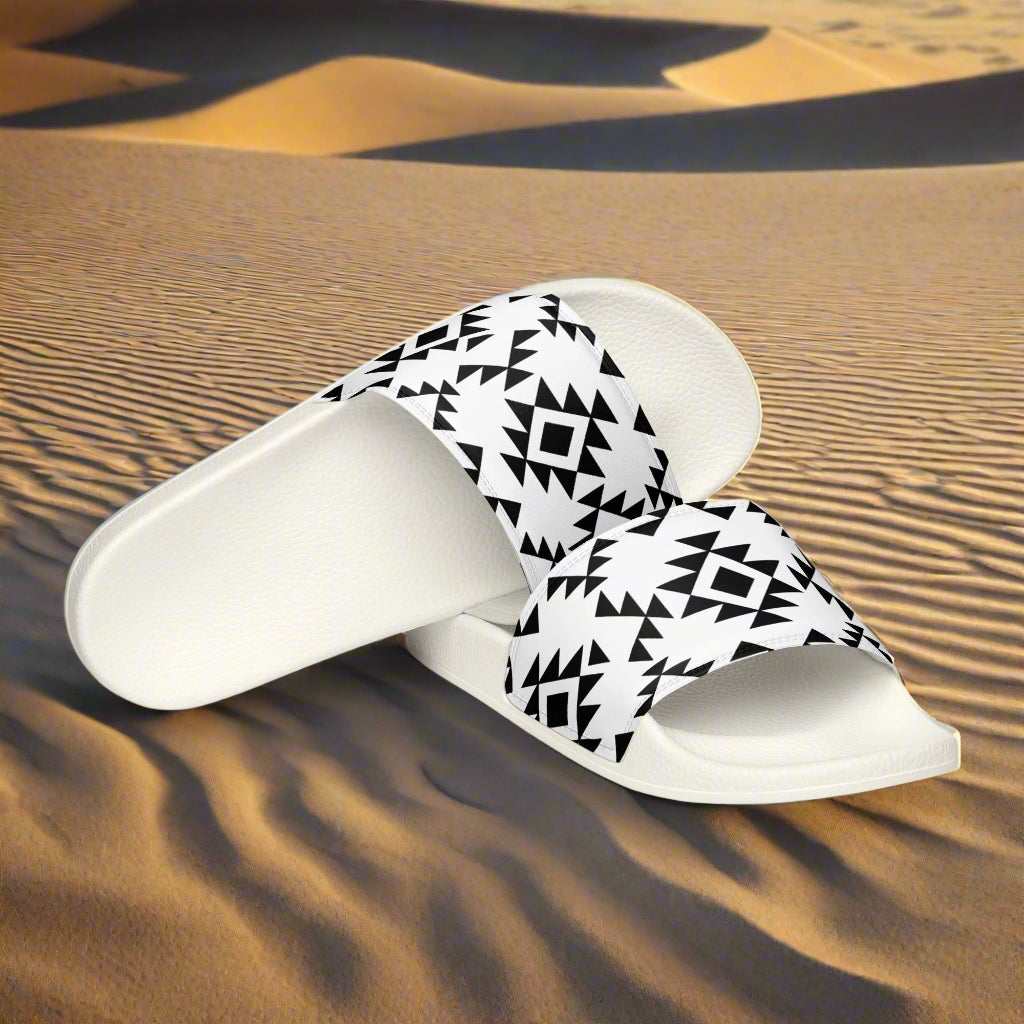 White slides with black Southwest pattern from WildSage Market on desert sand background