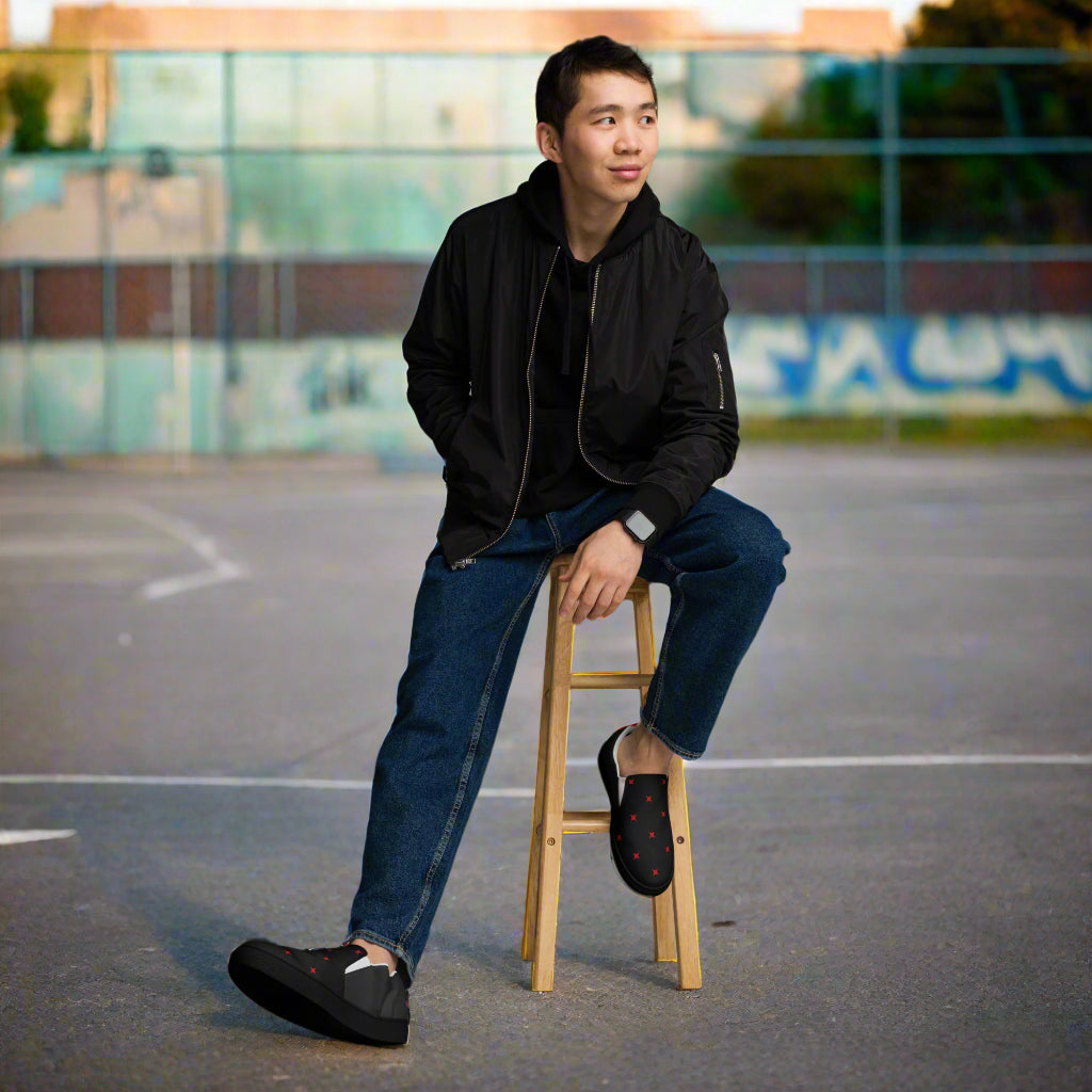 Young man wearing WildSage Market slip on canvas shoes crimson diamond black with red diamond pattern outdoors