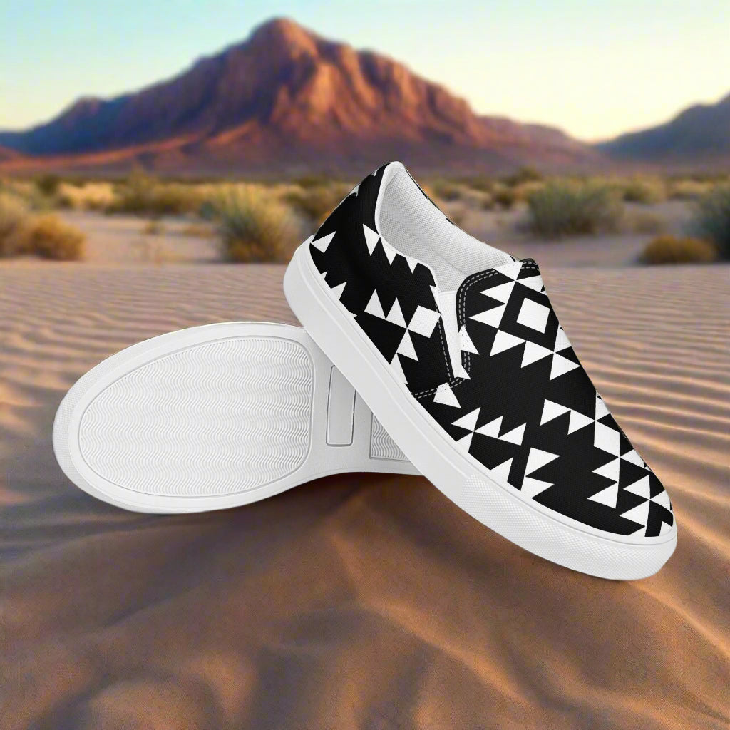 Southwest style mens slip-on shoes with a black and white geometric pattern on a sandy background