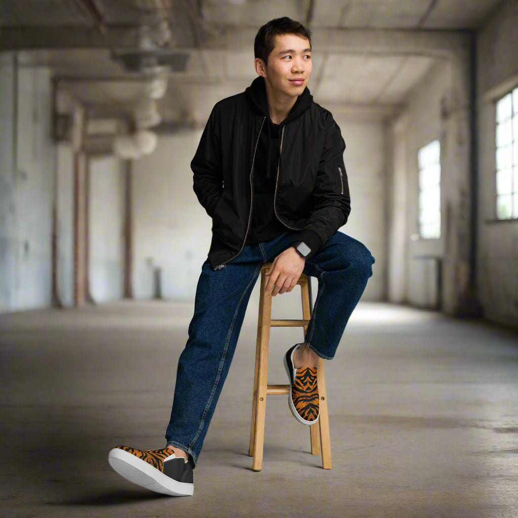WildSage Market slip on shoes with tiger halftone design worn by a man sitting on a wooden stool