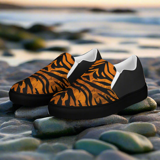 WildSage Market slip on shoes with tiger print halftone design and black soles on rocky beach