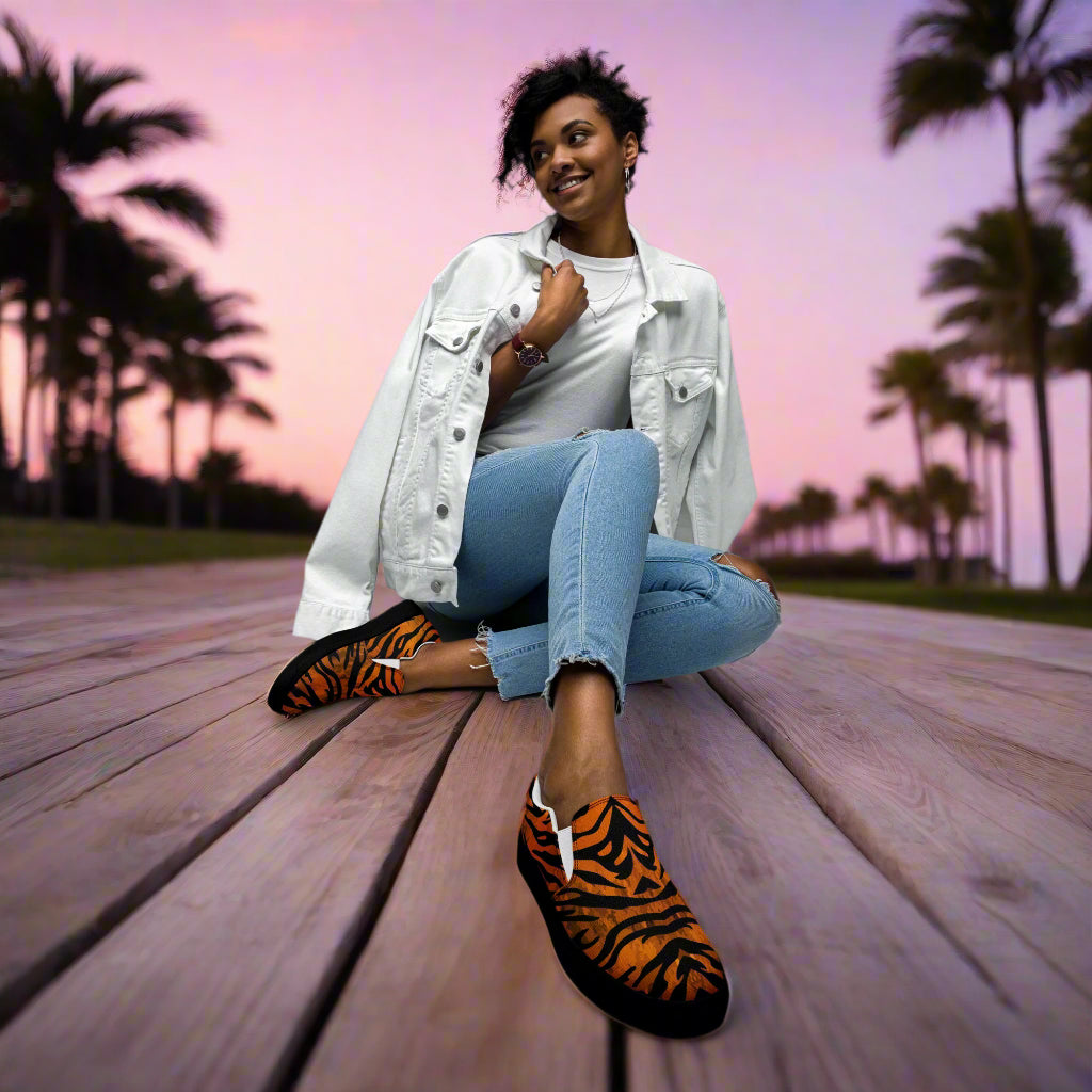 Woman sitting outdoors wearing tiger print slip on shoes with casual jeans and white jacket