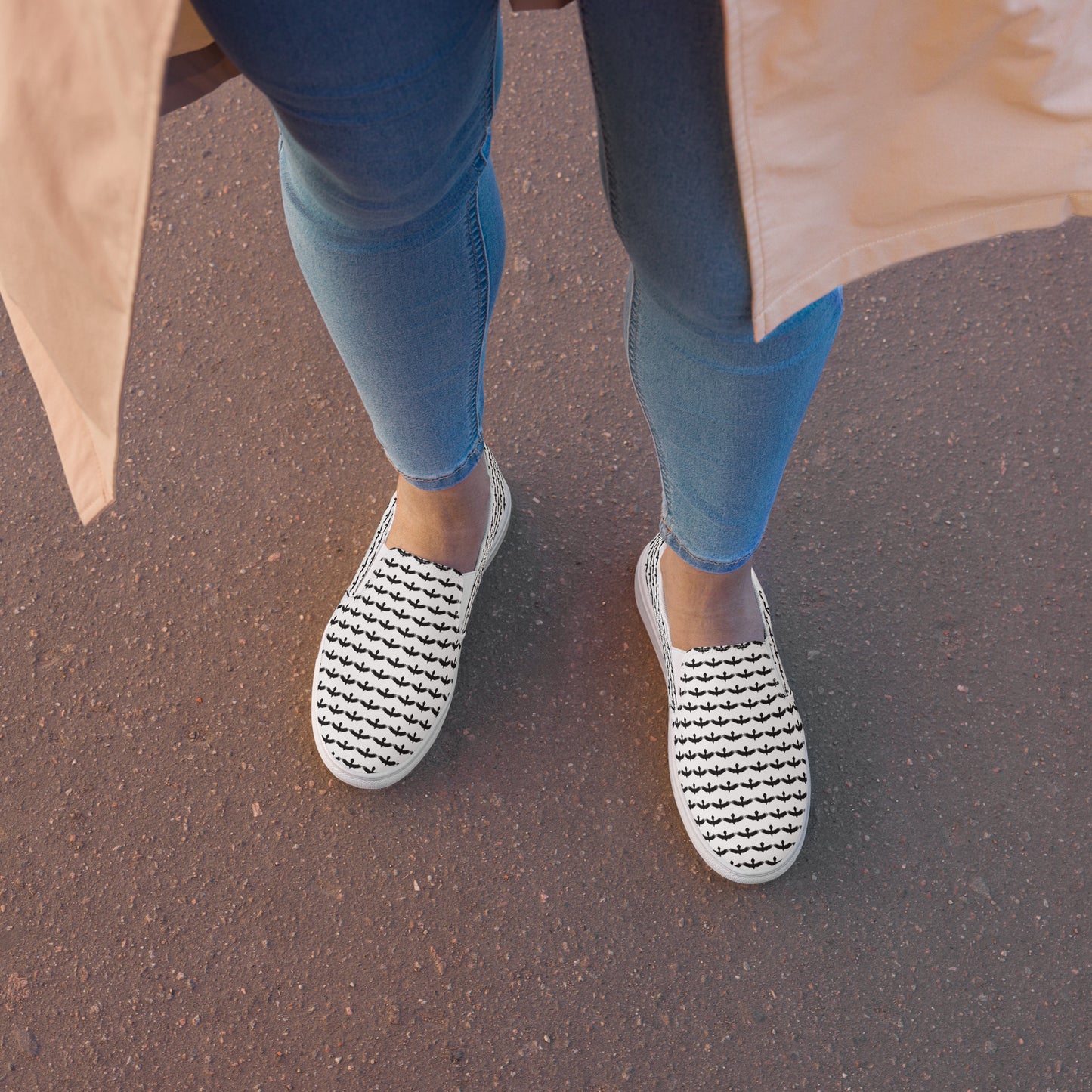 WildSage Market black raven pattern slip on shoes worn with blue jeans on asphalt surface
