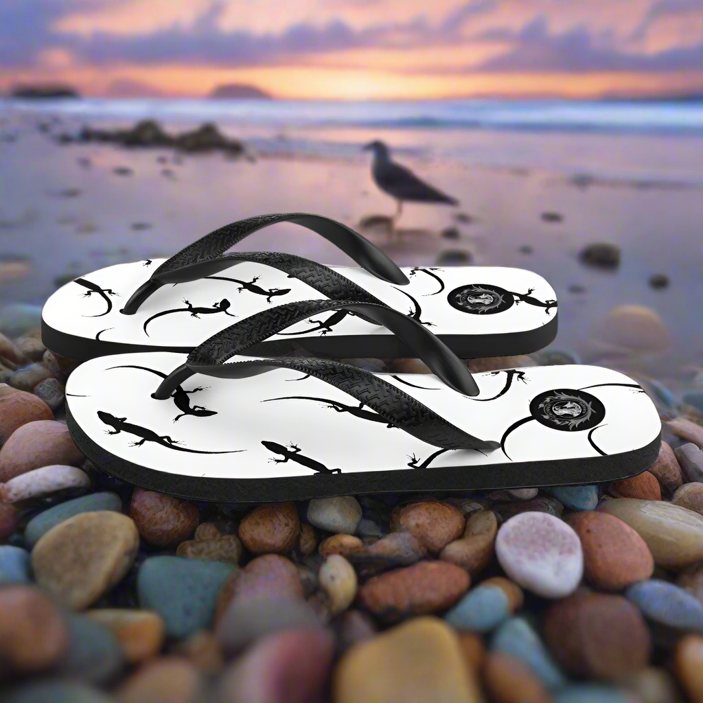 WildSage Market white lizard print flip-flops with black straps on a beach background