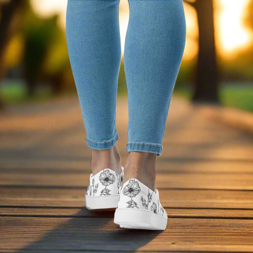 White Poppy Slip-on Canvas Shoes worn with denim jeans on a wooden deck