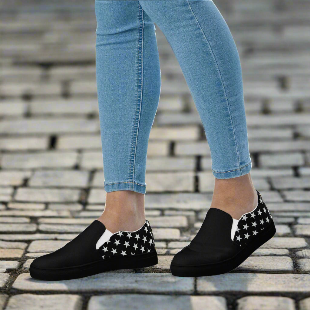 WildSage Market white star two tone slip on canvas shoes worn with light blue jeans on cobblestone pavement
