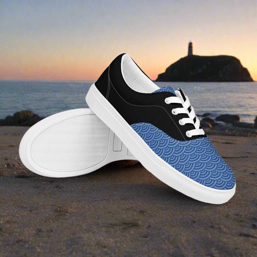 WildSage Market Custom Lace-up Canvas Shoes with blue wave pattern white laces and black trim on a beach at sunset