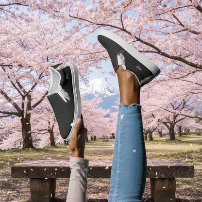 Black Crane Two Tone Slip-on Canvas Shoes showcased outdoors with cherry blossoms in the background