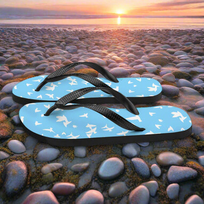 Blue white bird print flip-flops on a rocky beach at sunset for casual summer wear