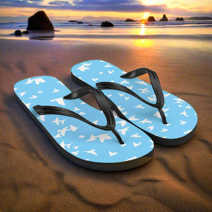 Blue white bird print flip-flops by WildSage Market on a sandy beach at sunset
