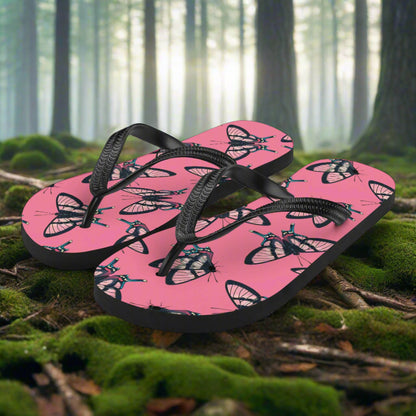 WildSage Market butterfly print flip-flops on a forest floor with vibrant pink design and black straps