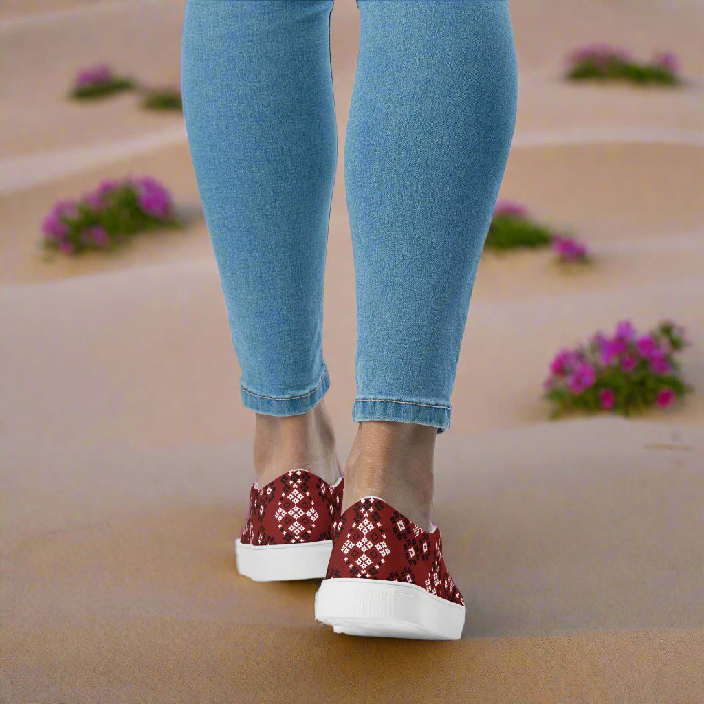 Woman wearing Slip-on Canvas Shoes Red Mesa Southwest Print with denim jeans, walking on a sandy path