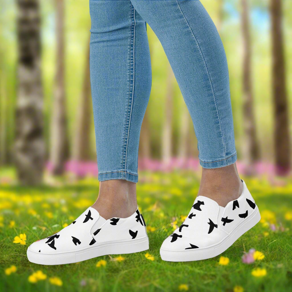 WildSage Market slip on shoes blackbirds pattern in white with black bird silhouettes worn with blue jeans outdoors