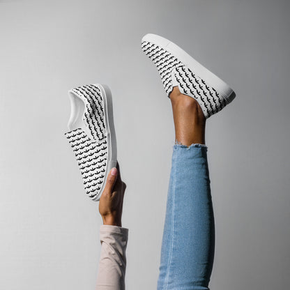 WildSage Market black raven pattern slip on shoes worn on foot and held up against gray background