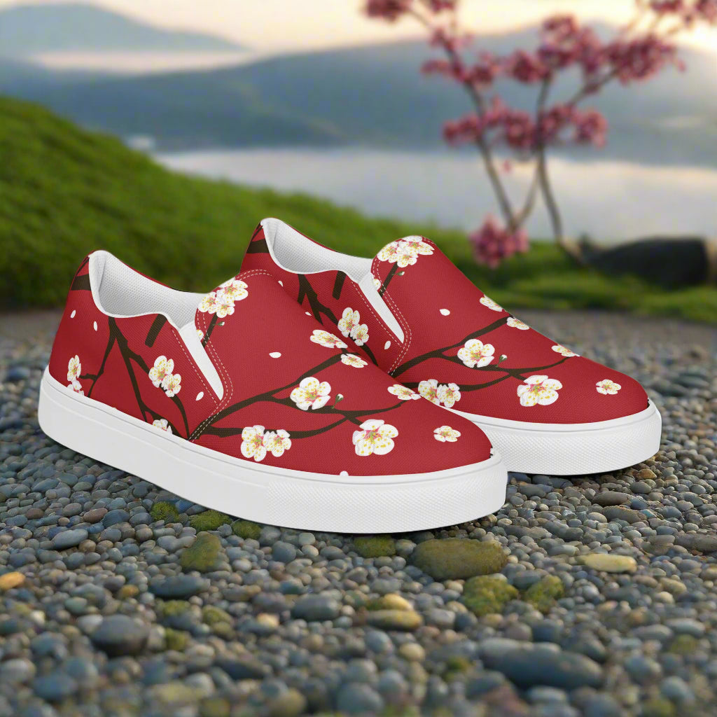 womens Red Blossom floral print slip on shoes by WildSage Market with white soles on pebbled ground